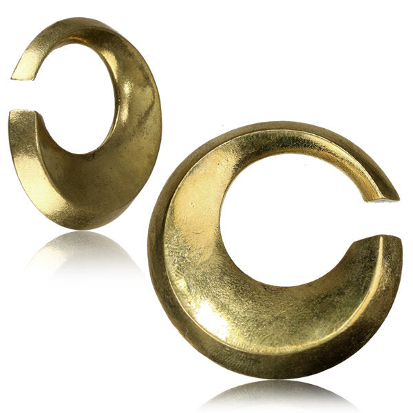 The HOLO Hoop Dangle Ear Weights in Gold by Kaya Movement are a pair of crescent-shaped, gold-colored earrings with a polished finish and an open gap design. Perfect for stretched ear lobes, these 6 gauge earrings feature a reflective surface and smooth texture, showcasing a bold and modern aesthetic.